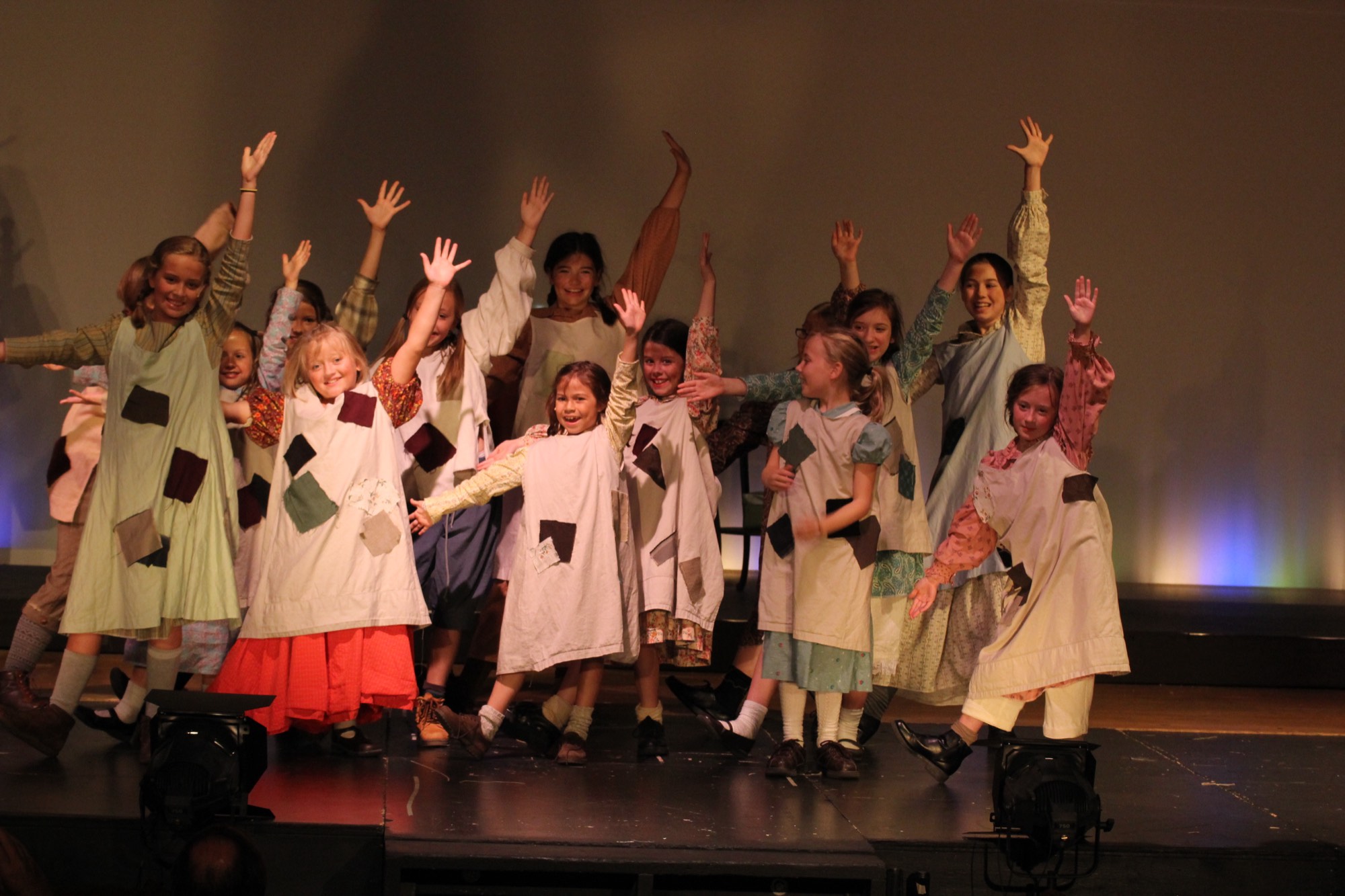 Young performers with arms raised during the 2022 production of Matilda.